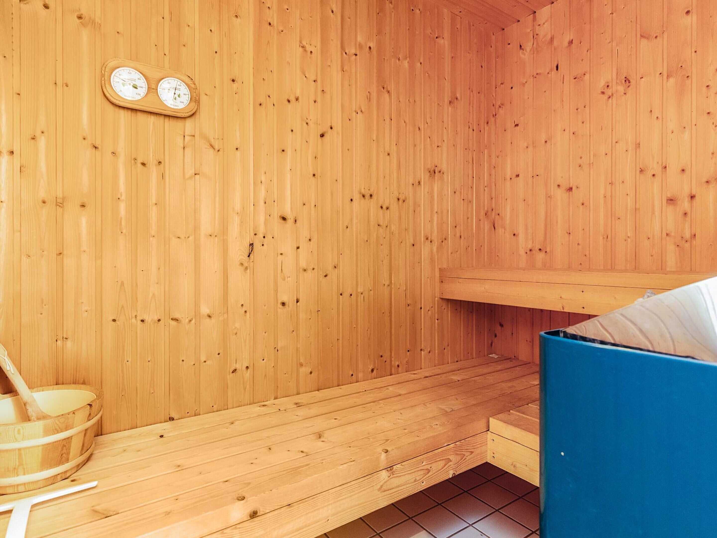 A wooden sauna with a bench, a wooden bucket, and a blue bench.
