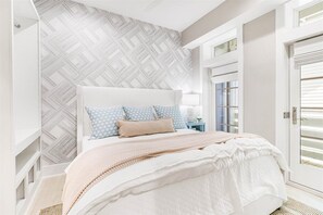 Een slaapkamer met een bed, behang met patroon, een nachtkastje en een deur.