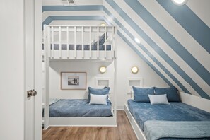 A bedroom with a bunk bed, two bedside tables, and a framed picture on the wall. - Ocean Paradise 245 DEW (Port Aransas)