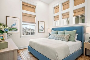 A bedroom with a large bed, a nightstand, a dresser, and two framed pictures on the wall. - Ocean Paradise 245 DEW (Port Aransas)