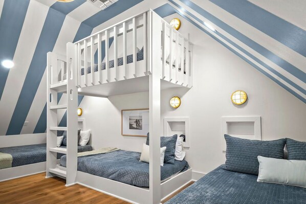 A bedroom with bunk beds, a staircase, and a ceiling with blue and white stripes. - Ocean Paradise 245 DEW (Port Aransas)