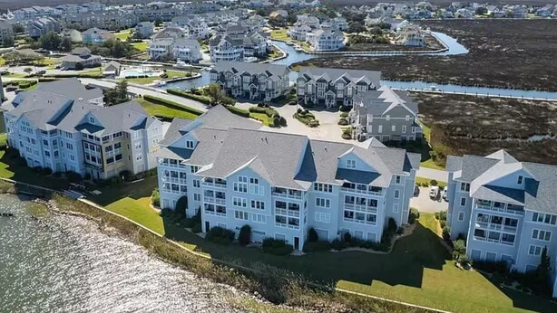 A coastal residential area with multiple two-story houses, a marina, and a large body of water. - A Pirates Life - Fishing, Boat Slip, Pool, Gym!  (Manteo)