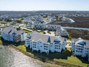 A coastal residential area with multiple two-story houses, a marina, and a large body of water.