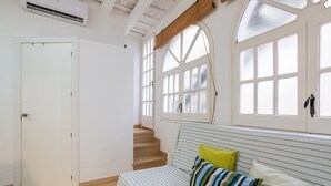 Une pièce avec un lit, un escalier et de grandes fenêtres.