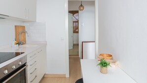 Une cuisine moderne avec des armoires blanches, une cuisinière en acier inoxydable et une planche à découper en bois.