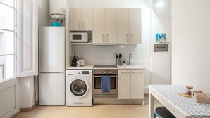 Une cuisine compacte équipée d’un lave-linge, d’un four à micro-ondes, d’un four et d’un évier.