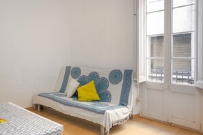 Ett rum med en säng, en bänk, en dörr med ett fönster och en sänggavel med ett mönster.