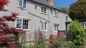 A two-story building with multiple windows, a chimney, and a garden with various plants and flowers. - The Spyway Inn (Dorchester)