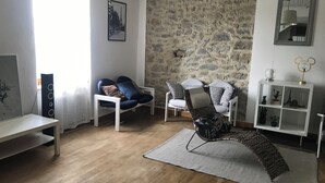 A living room with a stone wall, a white sofa, a patterned armchair, and a small white cabinet with decorative items.