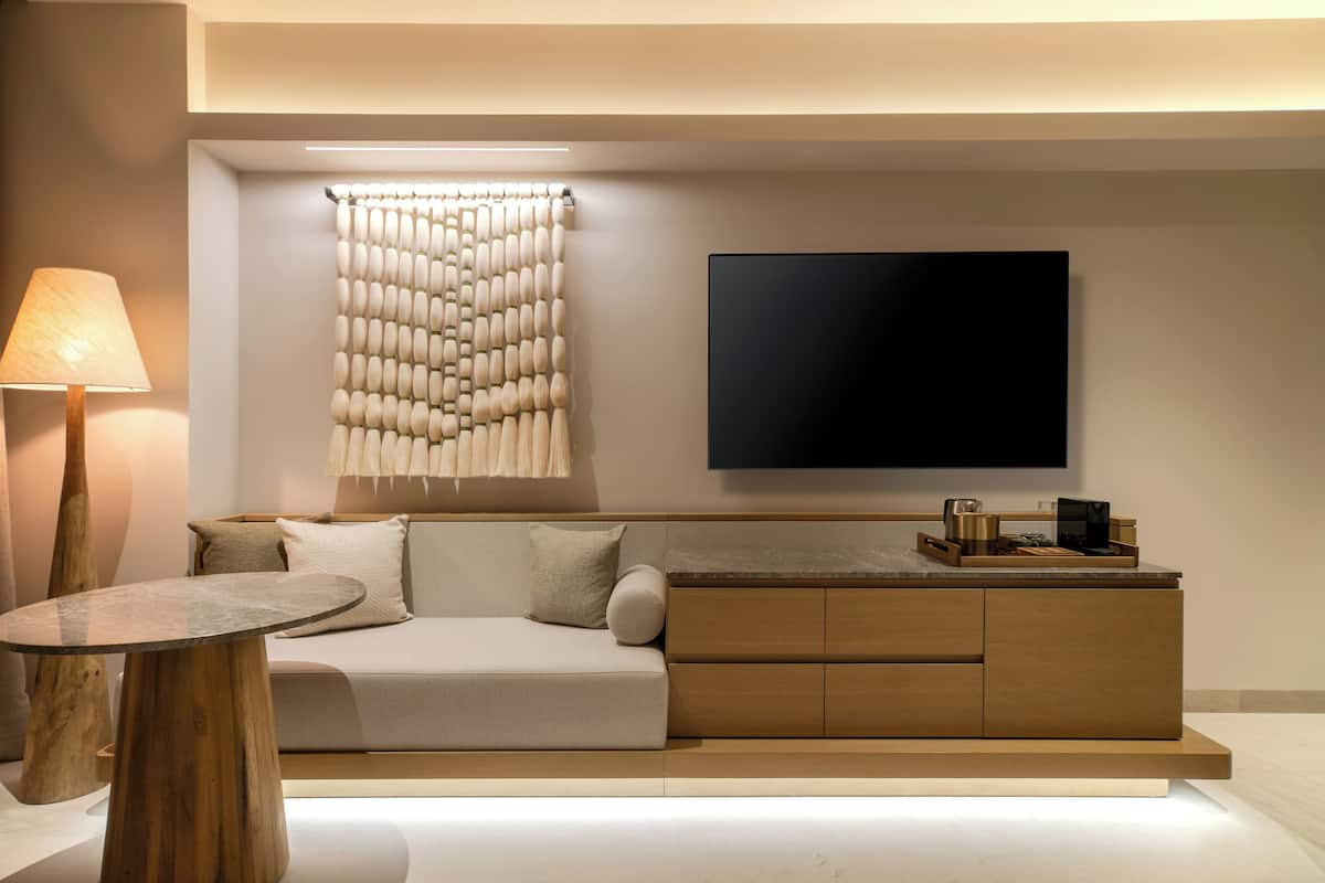 Een moderne woonkamer met een bank, een salontafel, een flatscreen-televisie aan de muur en een lamp.