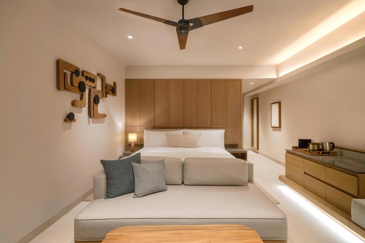 Een moderne slaapkamer met een bed, een houten plafondventilator, een nachtkastje en een inbouw houten kast.