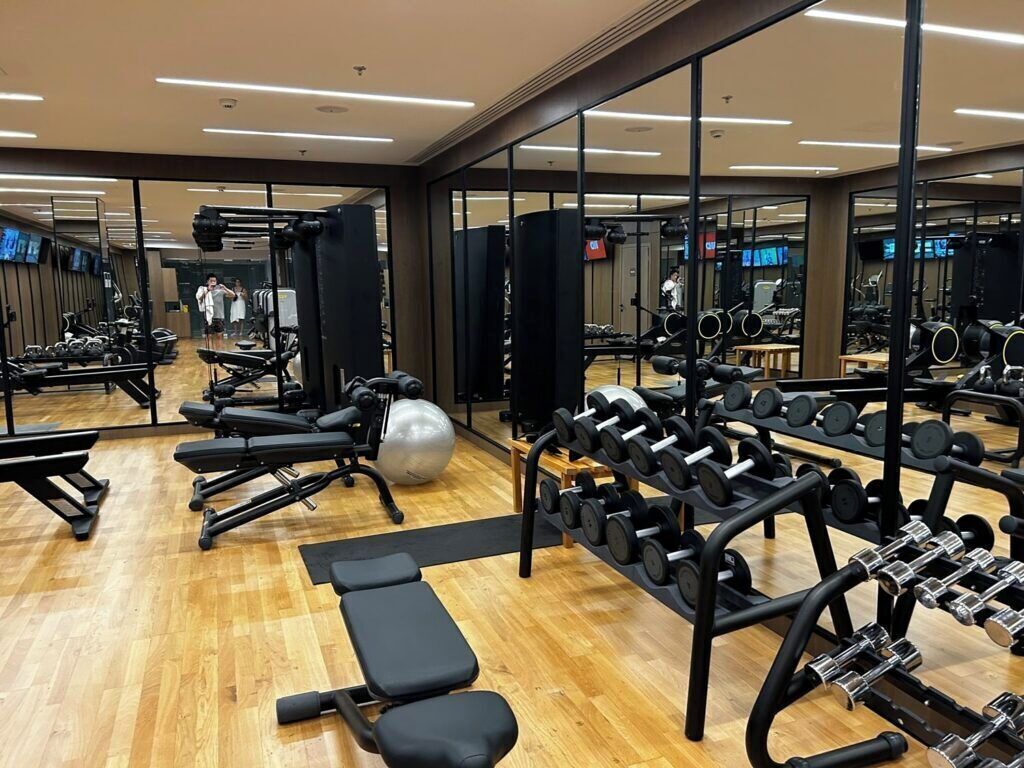 Une salle de sport équipée de matériel d’exercice, de miroirs et dotée d’un plancher en bois.