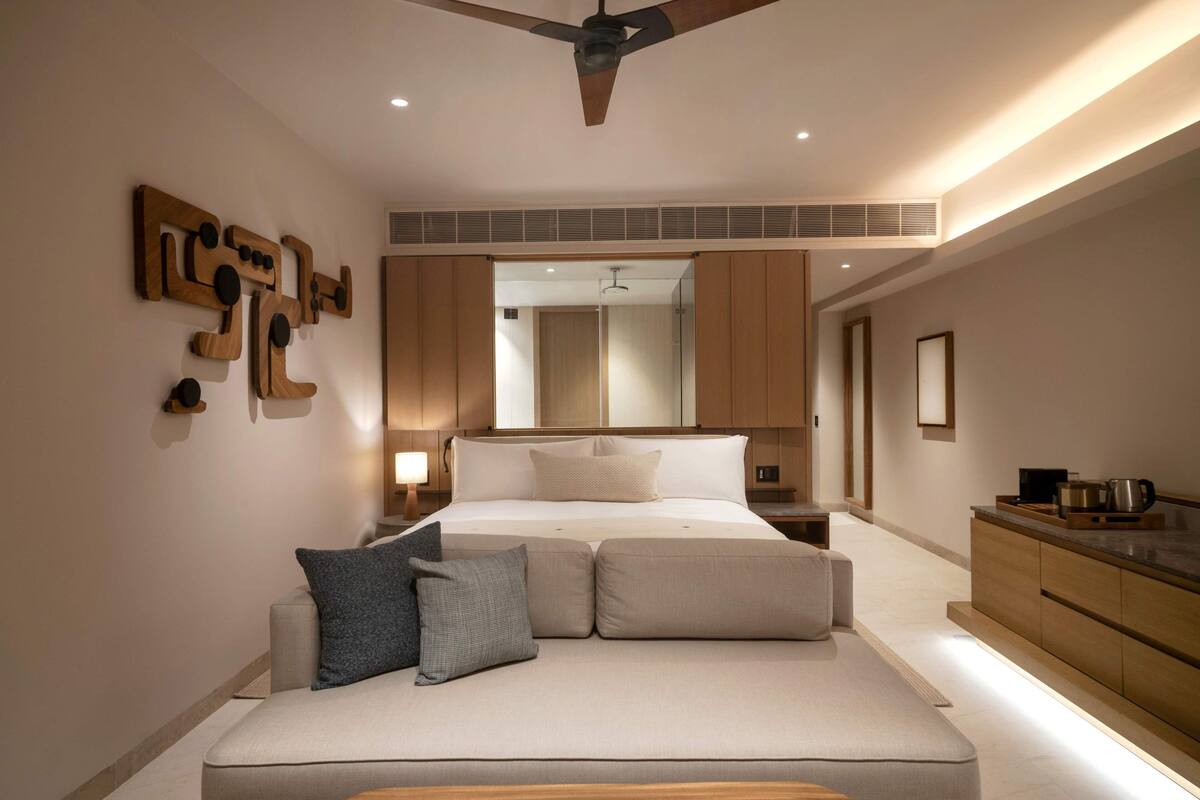 Een moderne slaapkamer met een groot bed, een plafondventilator, een inbouwkast en een nachtkastje met een lamp.