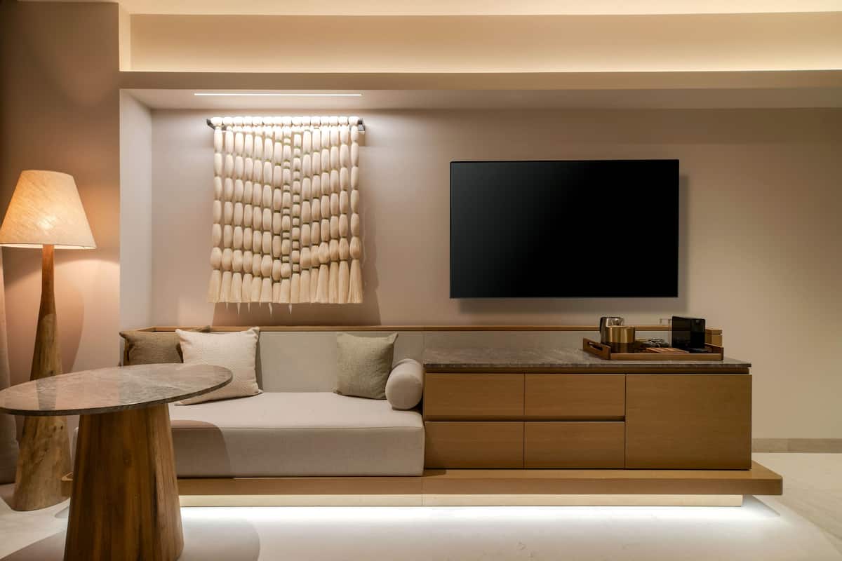 Een moderne woonkamer met een bank, een salontafel, een aan de muur bevestigde televisie en een lamp.