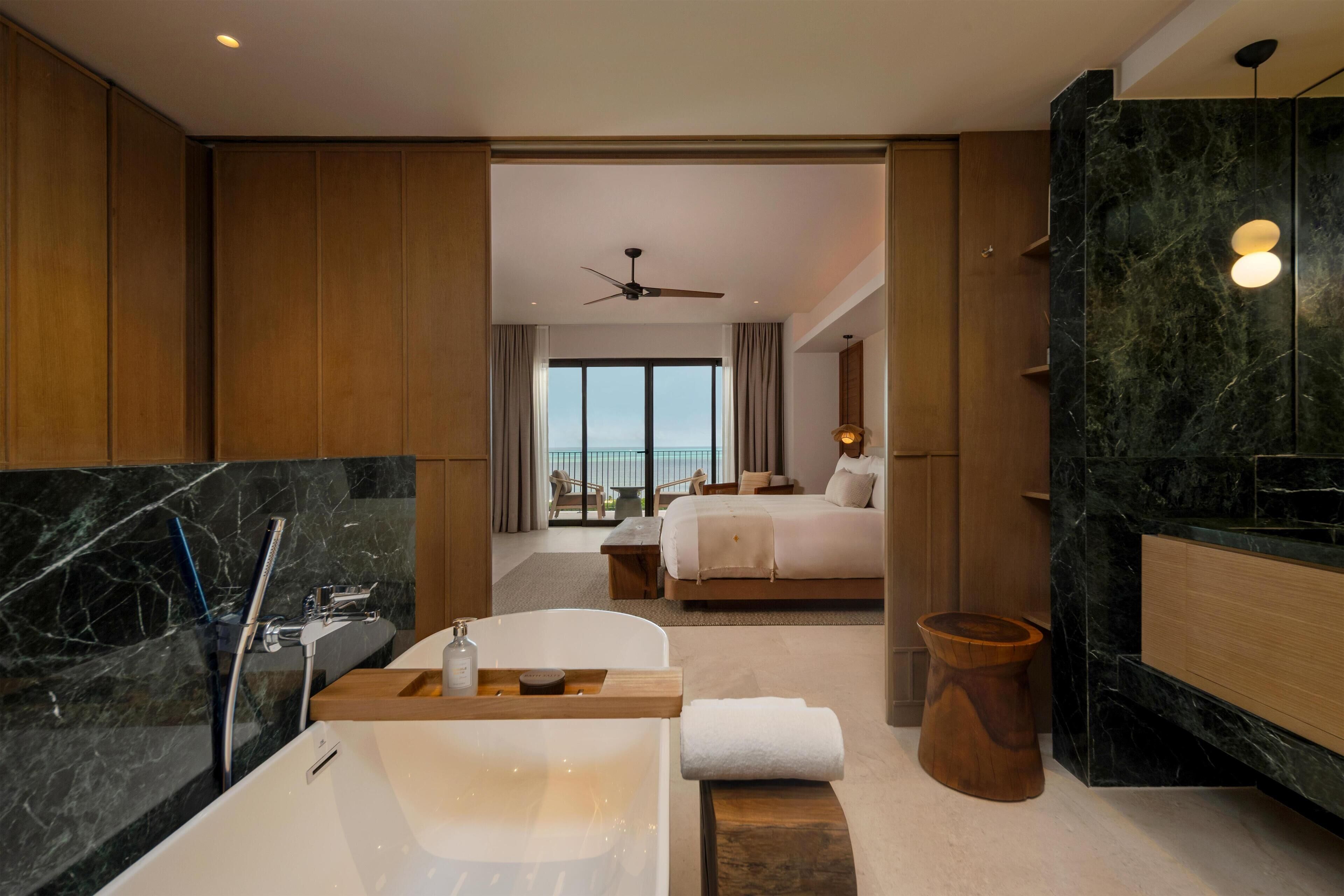 A modern hotel bathroom with a large bathtub, a separate shower area, and a wooden vanity.