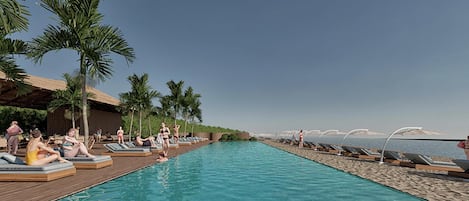 Un área junto a la piscina con sillones de descanso y palmeras, una terraza de madera y vistas al océano.