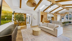 Ein geräumiges Wohnzimmer mit einer großen Couch, einem runden Couchtisch und Blick auf die Küche und den Essbereich.