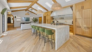 Eine geräumige Küche mit einer großen Kochinsel, Holzbalken und modernem Design.