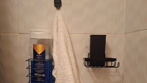 Une salle de bain avec une serviette suspendue à un porte-serviettes, un support à brosse à dents et des articles de toilette rangés sur des étagères.