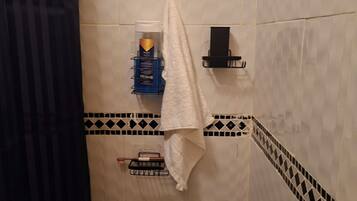 Een douche, handdoeken, zeep, toiletpapier