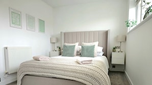 A neatly arranged bedroom with a large bed, two bedside tables, and a radiator. - 3BR - Luxury Home Away From Home - Contractor Digs - Near LGW Airport (Crawley)