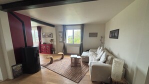 Una sala de estar con un sofá, una mesa de centro, un armario rojo, una chimenea y una ventana con cortinas.