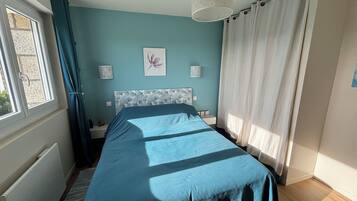 Ein Schlafzimmer mit einem Bett, einem Fenster, einer Heizung, einer Wandleuchte und einer Deckenlampe.