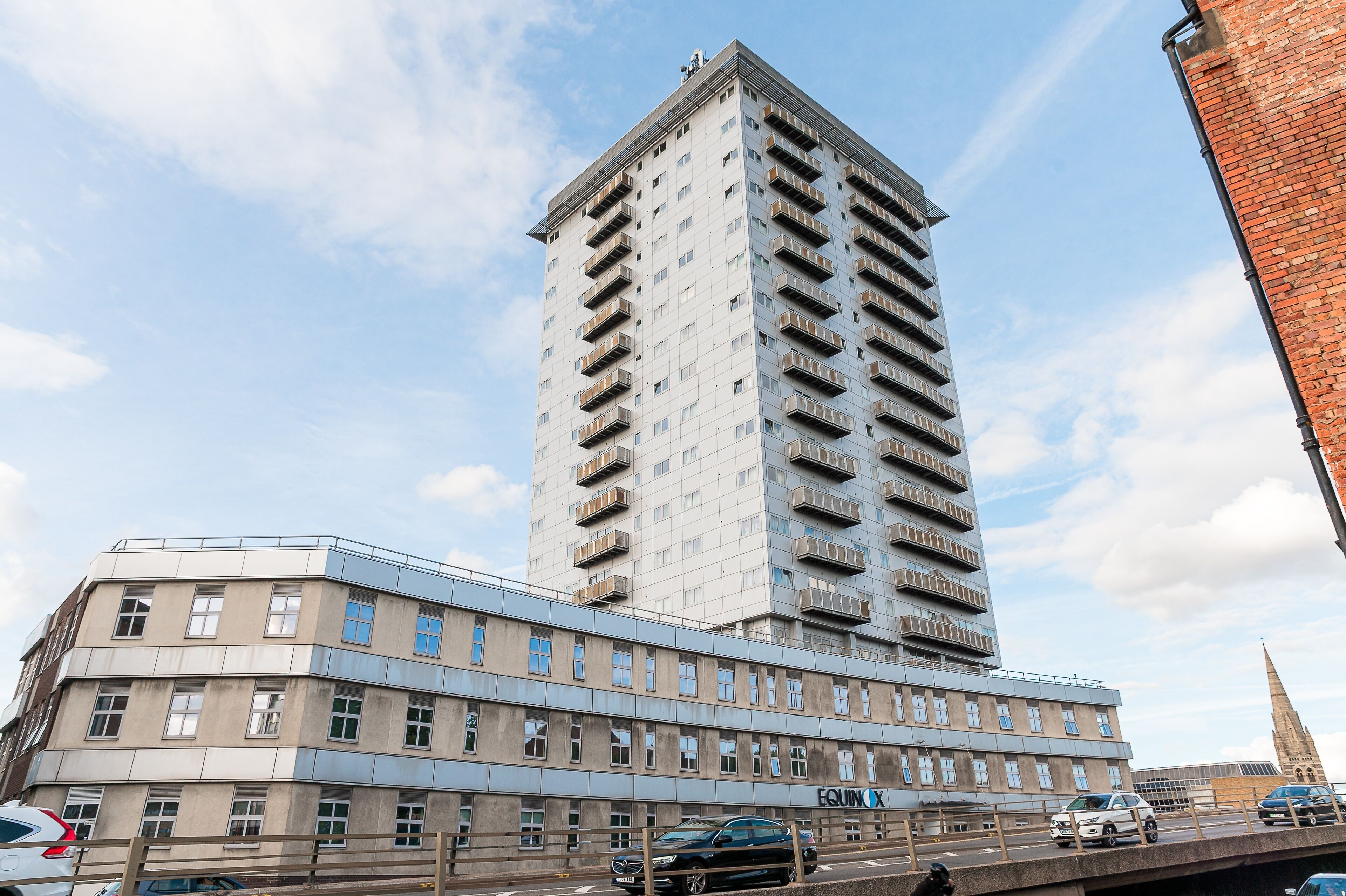 Un immeuble à plusieurs étages doté d’une architecture moderne, caractérisé par un toit plat et une série de balcons.