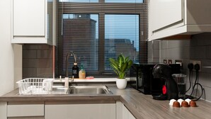 A modern kitchen with a built-in dishwasher, a coffee machine, and a potted plant. - Central Leicester Gem | Sleeps 5 | FREE PARKING (Leicester)