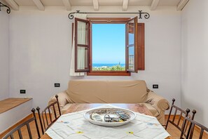 A room with a table, a sofa, and a window with an open shutter.