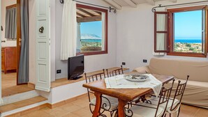 Una habitación con una mesa de comedor, sillas, un sofá, un televisor y vista al mar.