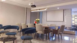 A modern conference room with a large table, several chairs, a projector, and a screen.