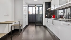 A modern kitchen with white cabinets, a black countertop, and a red appliance.