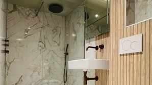 A modern bathroom with a marble floor, a glass-enclosed shower, a white sink, and a toilet. - Amigo Hotel (Amsterdam)