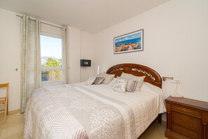 A bedroom with a bed, a dresser, a window with curtains, a painting on the wall, and a view of the outdoors. - Apartment 'Cal Albir Atico' with Shared Pool, Wi-Fi and Air Conditioning (albir)