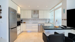Eine moderne Küche mit Kühlschrank, Mikrowelle, Backofen, Geschirrspüler und einem Essbereich mit Tisch und Stühlen.