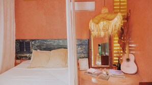 Une chambre à coucher avec un lit, une table de chevet sur laquelle se trouve une guitare, un miroir et un luminaire suspendu.