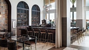 A modern bar area with a high bar counter, multiple stools, and a large window with decorative iron grilles. - Cozy resort in enchanting Carlsbad at the flower fields (Carlsbad)