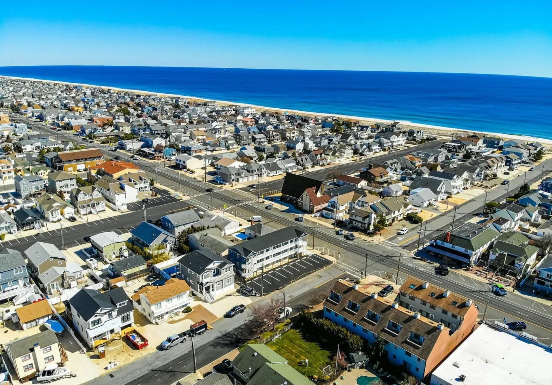 Vue aérienne d’une zone résidentielle côtière, avec des maisons, des routes et une plage.