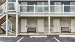A building with a balcony, three doors, and two benches. - Cozy 1-bedroom condo in Lavallette, located 1 block from beach (Lavallette)