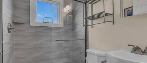 Un baño moderno con ducha de vidrio, inodoro y lavamanos.