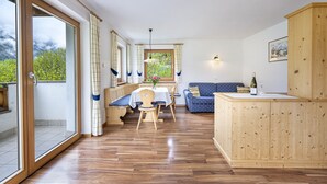 A spacious room with a wooden floor, a dining table with chairs, a sofa, and a wooden cabinet. - 1006A Apartments Ciancel Gino (Ortisei)