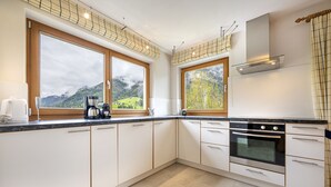 A modern kitchen with large windows, a built-in oven, and a view of a mountainous landscape. - 1006A Apartments Ciancel Gino (Ortisei)
