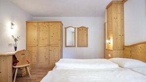 A bedroom with a wooden wardrobe, a desk with a chair, and a bed. - 1006A Apartments Ciancel Gino (Ortisei)