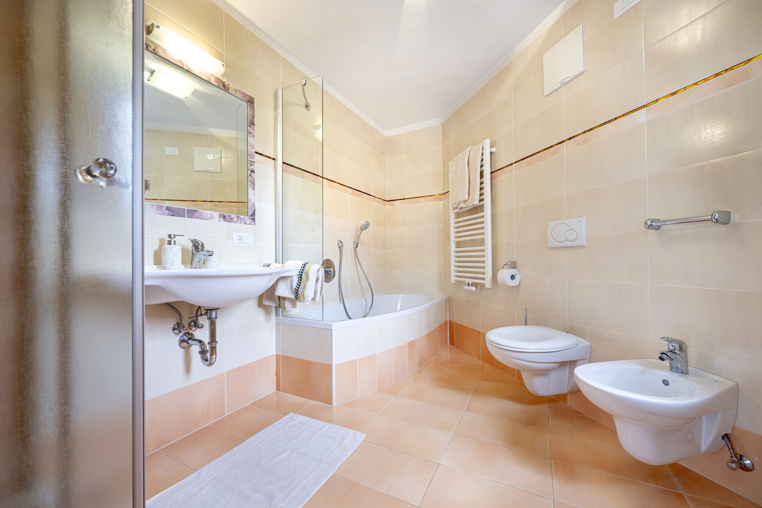 Un baño moderno con cabina de ducha de vidrio, una bañera independiente, inodoro y bidé.