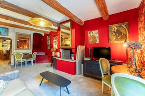 A living room with red walls, a TV, a bench, and a fireplace.
