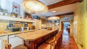 Een keuken met een bar, houten stoelen, een magnetron en een grote geweven lamp.