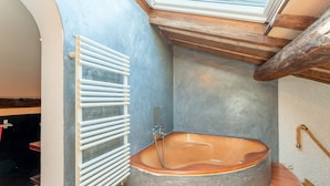 Een badkamer met een vrijstaand bad, een witte radiator en een dakraam.