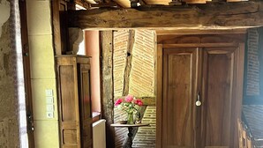 A rustic room with a tiled floor, wooden cabinets, and a vase with flowers on a small table. - House near the canal (Meilhan-sur-Garonne)