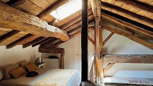 A rustic attic bedroom with exposed wooden beams, a sloped ceiling, and a view of the sky through a skylight. - House near the canal (Meilhan-sur-Garonne)
